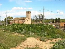Church in Montortal with greenery and blue sky with clouds.