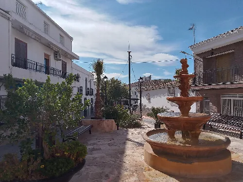 Fuente en la plaza de la Constitución de Taberno con bancos y edificios cercanos.
