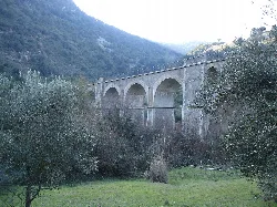 Stone viaduct with arches in a green, mountainous landscape.