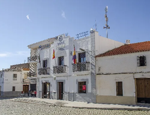 Weißes Gebäude mit Flaggen und Balkon in Higuera de la Serena.