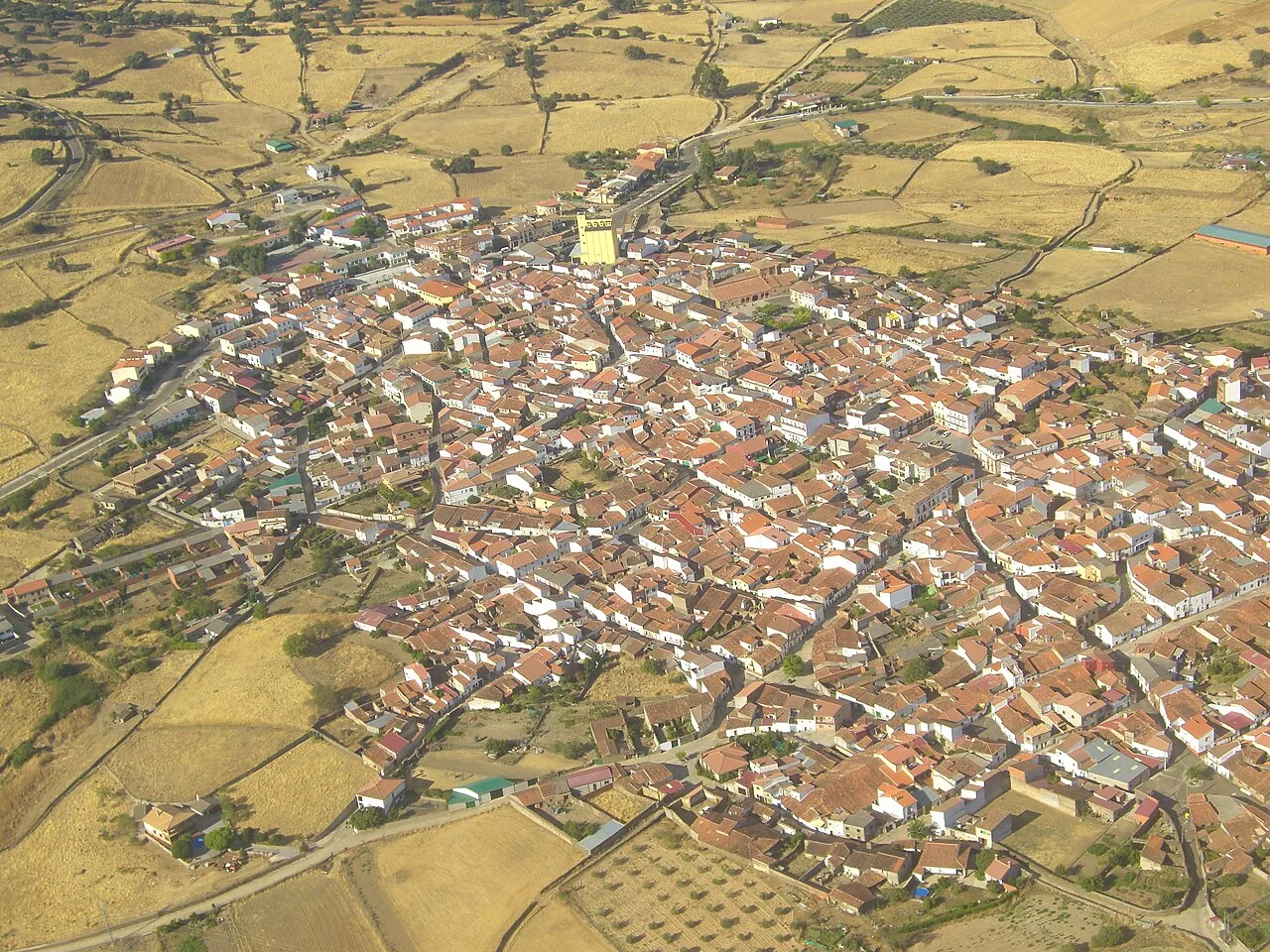 Luftaufnahme einer Stadt mit engen Straßen und roten Ziegeldächern.