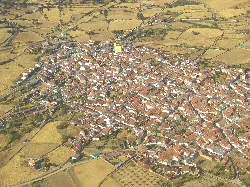 Vista aérea de un pueblo con calles estrechas y casas con tejados rojos.
