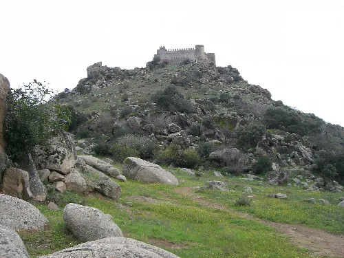 Burg auf einem Hügel mit Steinen und Vegetation.