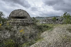 Betonbunker in einer ländlichen Landschaft mit Wegen und Vegetation.