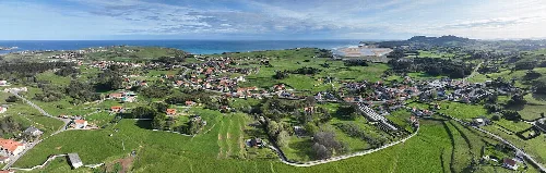 Paisaje panorámico de Miengo con casas, campos y mar en el horizonte.
