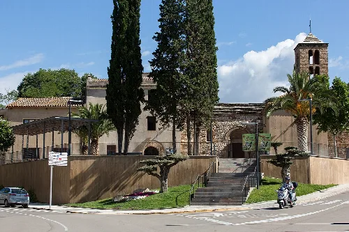 Kirche von Sant Pere mit Bäumen und Motorrad auf der Straße.
