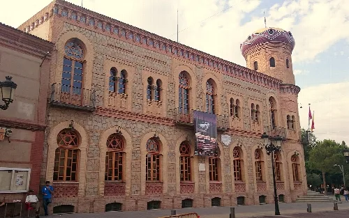 Edificio del ayuntamiento con torreón y ventanas arqueadas en Mora.