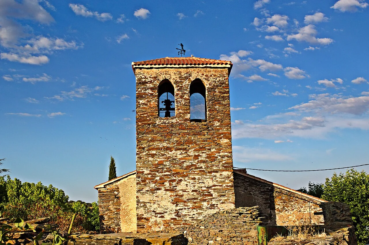 Kirchturm in Aldeavieja de Tormes mit blauem Himmel und Wolken.