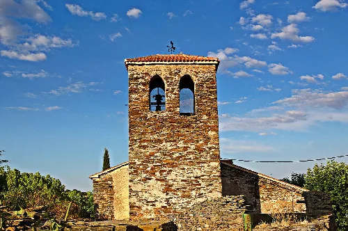 Torreón de la iglesia en Aldeavieja de Tormes, con cielo azul y nubes.
