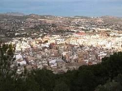 Vista de Yecla con edificios y montañas en el fondo.