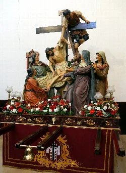 Escultura de la crucifixión con figuras religiosas en una iglesia.