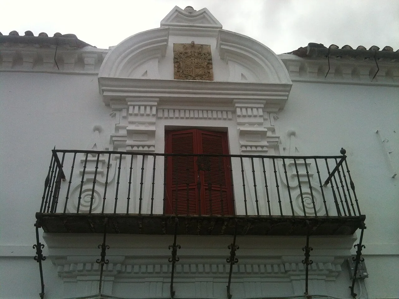 Fachada blanca con balcón y ventana con molduras en Siruela.