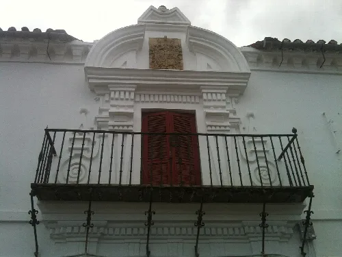 Weiße Fassade mit Balkon und Fenster mit Verzierungen in Siruela.