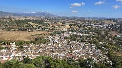 Vista aérea de Jimena de la Frontera desde el castillo, con casas blancas y montañas al fondo.