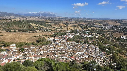 Luftaufnahme von Jimena de la Frontera vom Schloss, mit weißen Häusern und Bergen im Hintergrund.