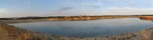 Panoramic view of Arauzo de Salce reservoir with water and clear sky.