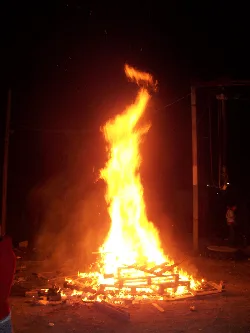 Gran fuego en Gilena con llamas altas y madera ardiendo.