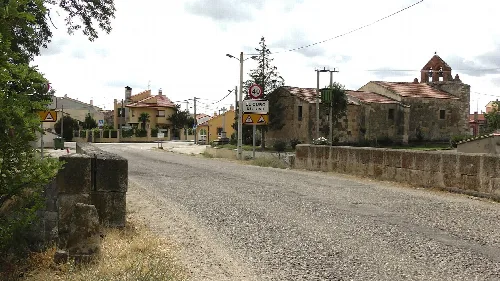 Ansicht des Dorfesingangs mit Häusern und einer Kirche im Hintergrund