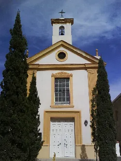 Facade of a church with white door and two cypresses on sides in Fortuna, Murcia.