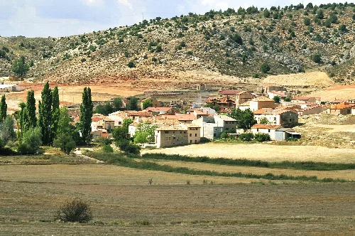 A village with houses and trees in a rural landscape with hills.