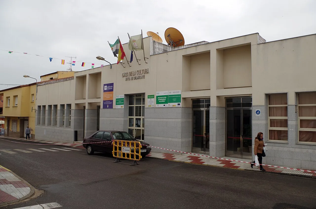 Edificio del Palacio de la Cultura en Calamonte con banderas y personas en la acera.