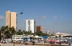 Hohe Gebäude, Palmen und Touristen am Strand von Santiago de la Ribera.