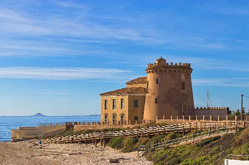 Torre de la Horadada am Strand mit blauem Himmel und Meer.