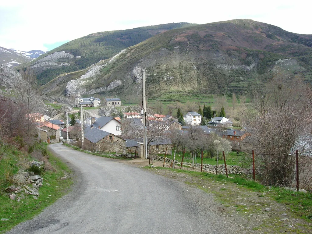 Dorf Lugueros mit Häusern, Kirche und Bergen im Hintergrund.