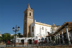Vista lateral de una iglesia con torre y fachada blanca en Paterna del Campo.