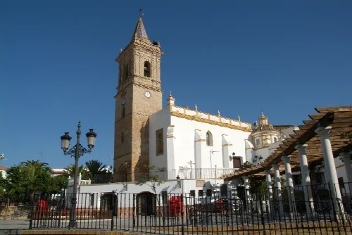 Lateral view of a church with tower and white facade in Paterna del Campo.