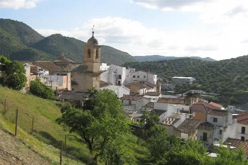 Landschaft von Algarinejo mit weißen Häusern, Kirche und grünen Hügeln.
