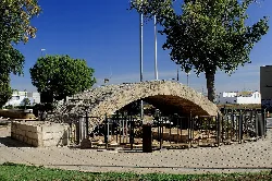 Puente romano de piedra en Alboraya con árboles y valla de protección.