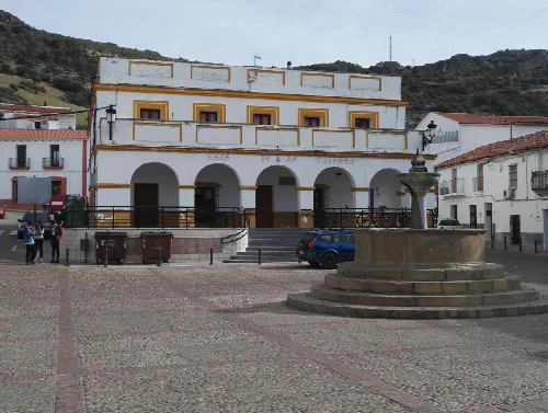 Platz mit Brunnen und weißem Gebäude mit Bögen in Esparragosa de Lares.