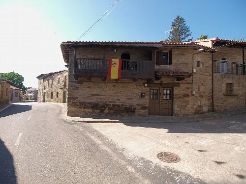 Steinhaus mit Balkon und spanischer Flagge in Villardeciervos.