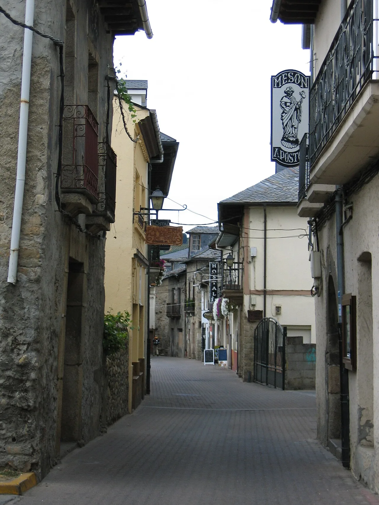 Enge Straße in Cacabelos mit alten Gebäuden und einem Mesón-Schild.