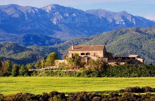 Katalanisches Bauernhaus in La Baronia de Rialb mit Bergen im Hintergrund.