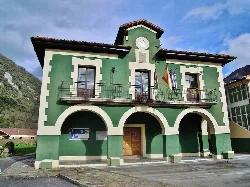 Edificio verde con arcos y banderas en Santo Adriano.