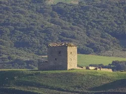 A stone tower in a green hilly landscape.