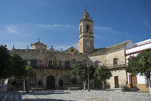 Town hall with tower and clock in the main square of Lora del Río.