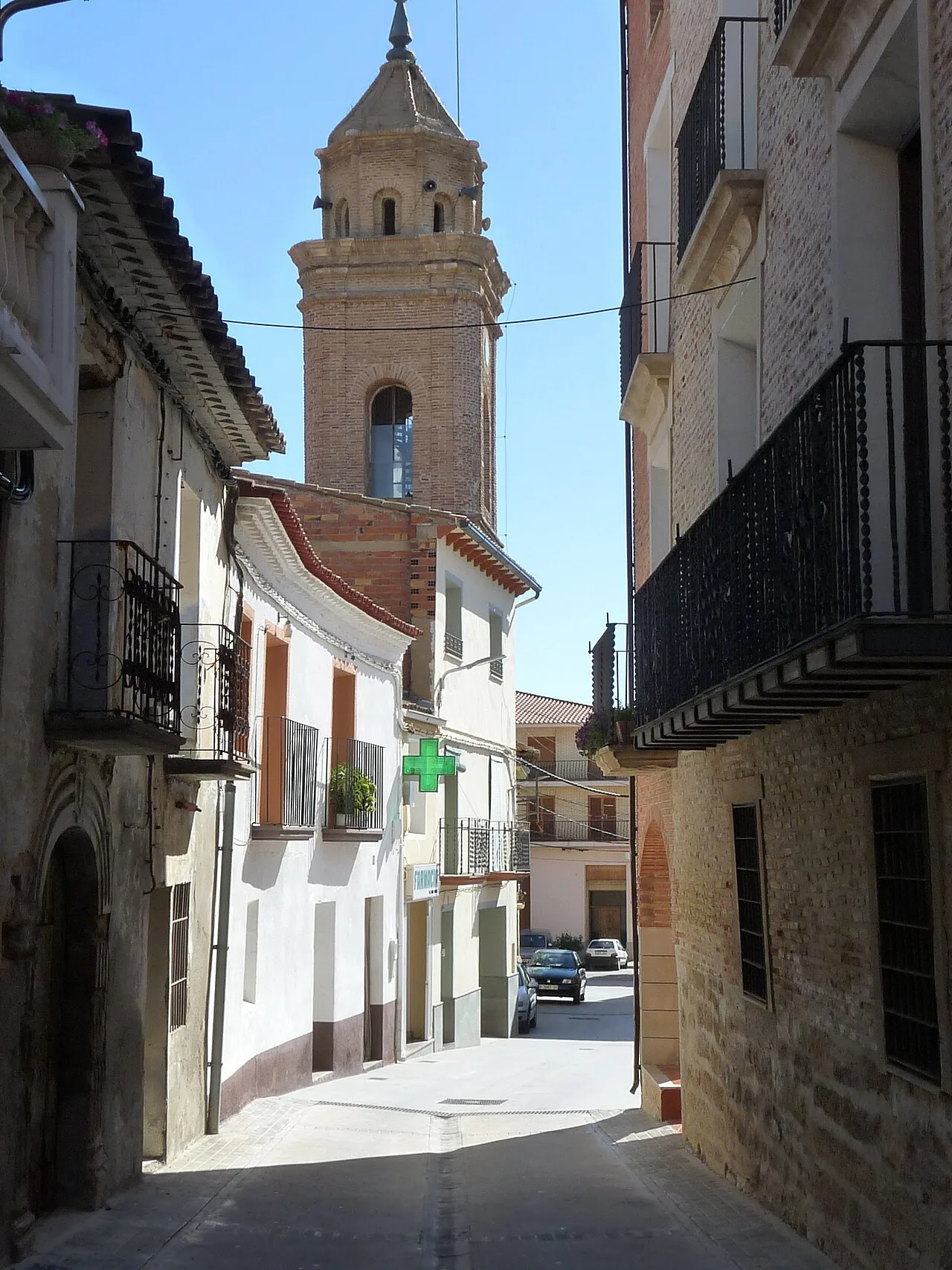 Vista de la calle estrecha con edificios y la torre de la iglesia al fondo.