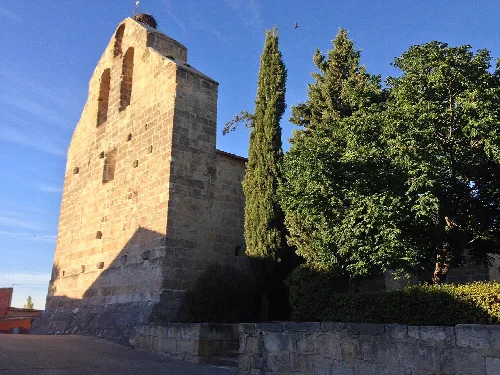 Steinerner Kirchturm mit grünen Bäumen in Santa Clara de Avedillo.