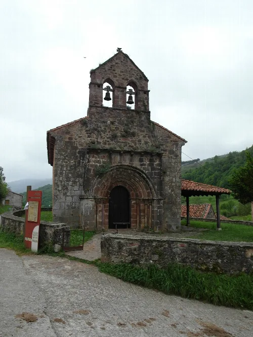 Iglesia románica de piedra con campanario y arco de entrada en Lamasón.