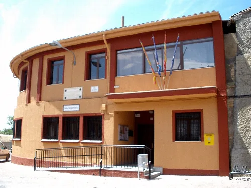 Town hall building with yellow facade and black barred windows.