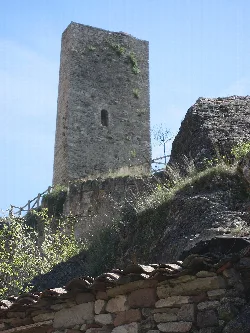 Steinturm in Anguita mit Vegetation und Steinmauer im Vordergrund.