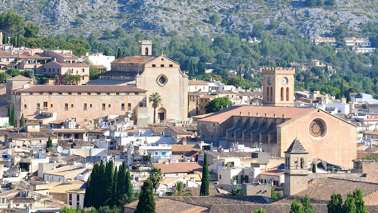 Roofs and churches in Pollensa with green hills behind