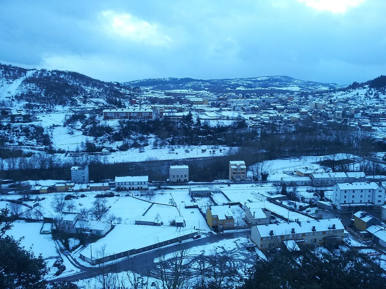 Landscape of Toreno with houses and snow-covered mountains on a snowy day.