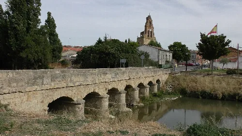 Steinbrücke über einem Fluss mit einer Kirche im Hintergrund in Venialbo.