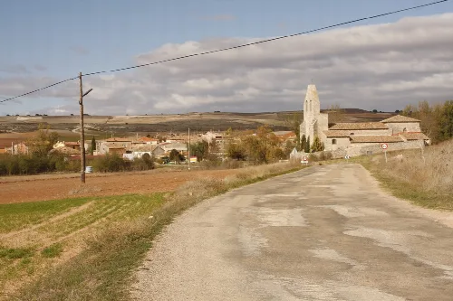 Dirt road with church and village in the background.