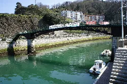 Alfonso XIII bridge over the Artibai River with boats in the water.