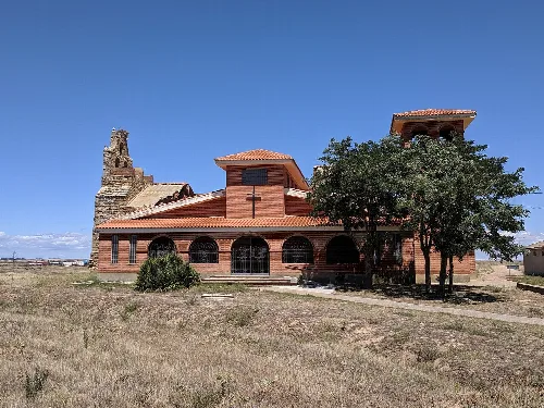 Kirchen in Quintanilla del Monte mit Baum und blauem Himmel.